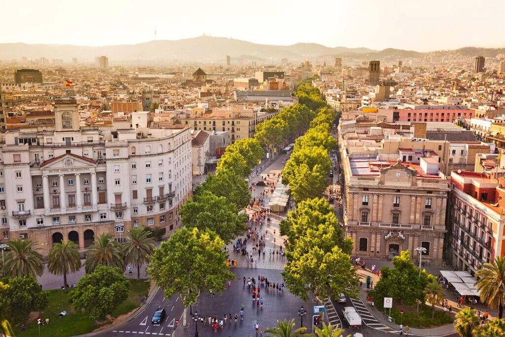 Vy över Barcelona, Spanien, med äldre hus och en bred gata kantad av träd.