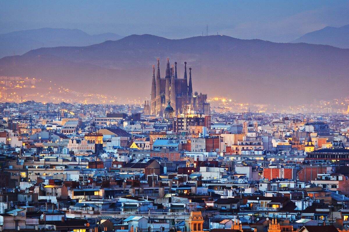 City vy över Barcelona på kvällstid, med ett stort berg bakom den berömda Gaudi katedralen.