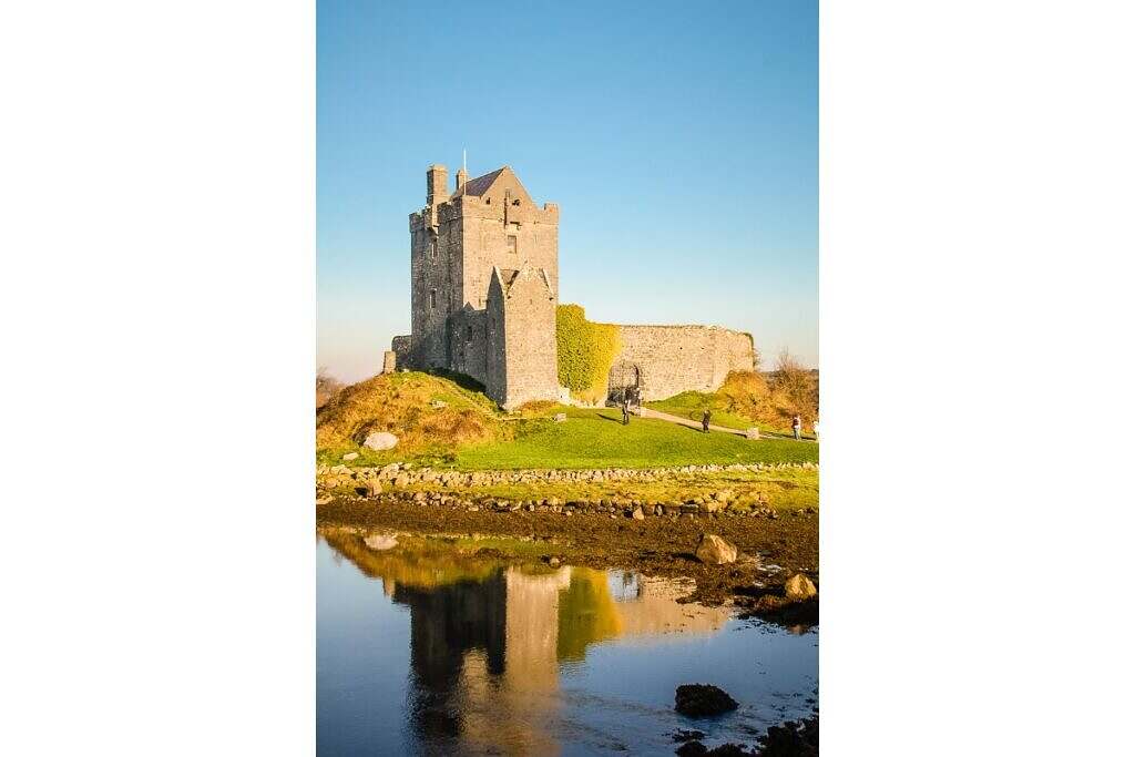 Dunguaire slott på Irland står på en grön mark med vatten framför.