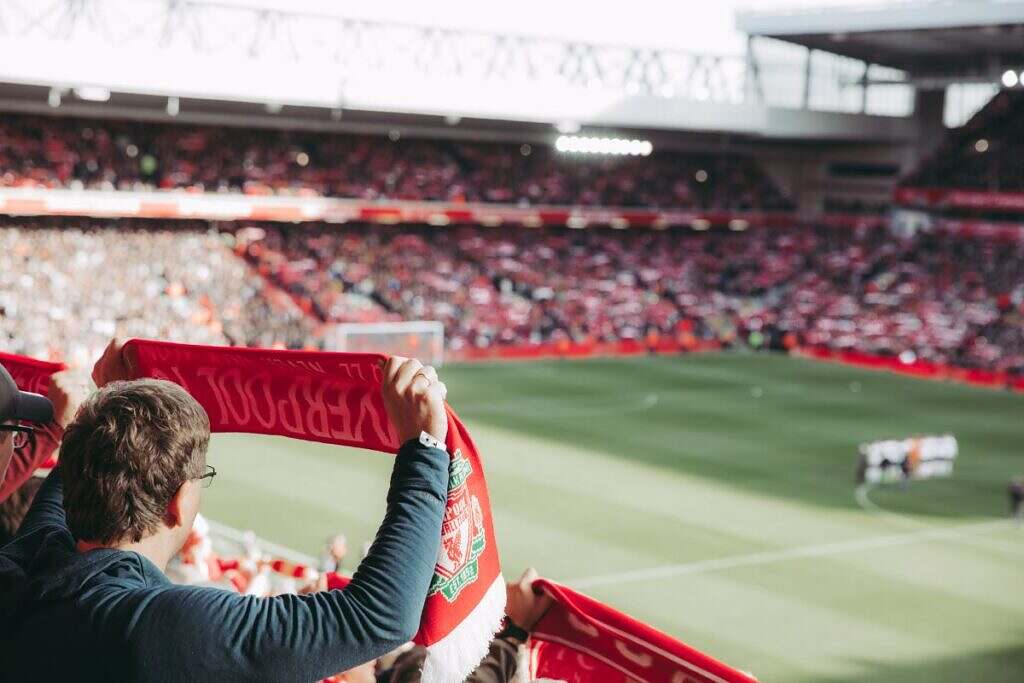 Ett fotbollsfans för Liverpool håller upp en halsduk inför en match.