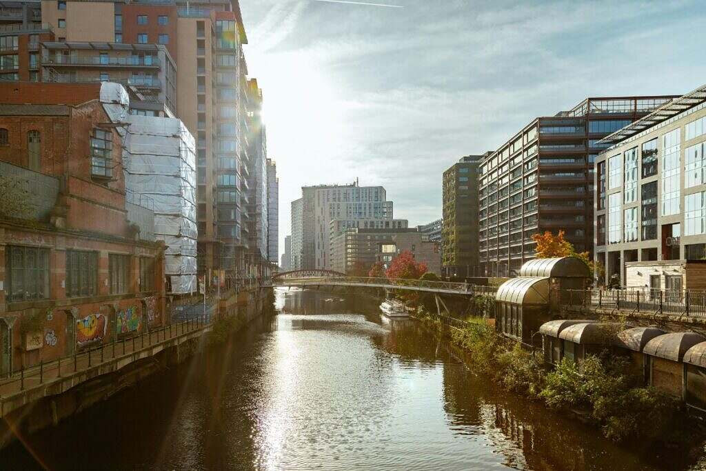 Vy över centrala Manchester med moderna höghus utmed båda sidorna av en å.