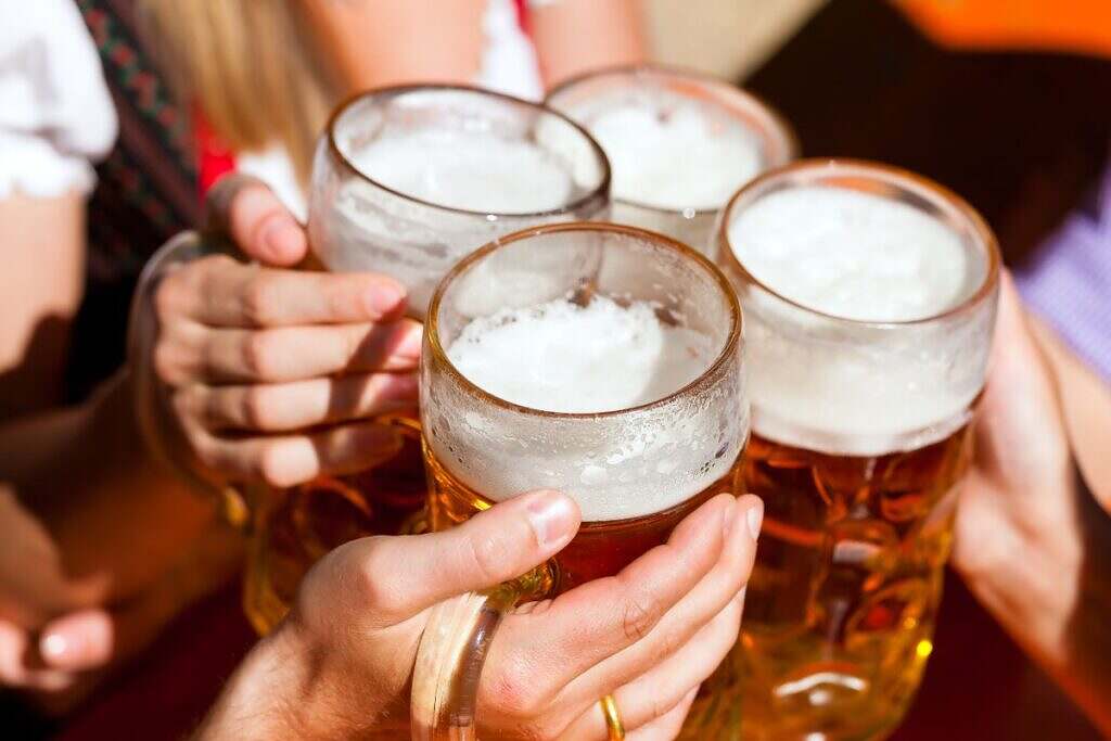 Fyra glas med öl som skålar under Oktoberfest i Munchen, Tyskland.