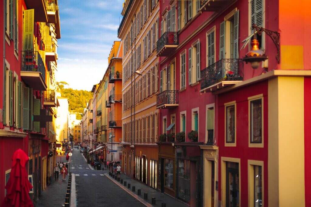 Vackra röda och orangfärgade klassiska bostadshus i Nice, Frankrike på en smal gata.