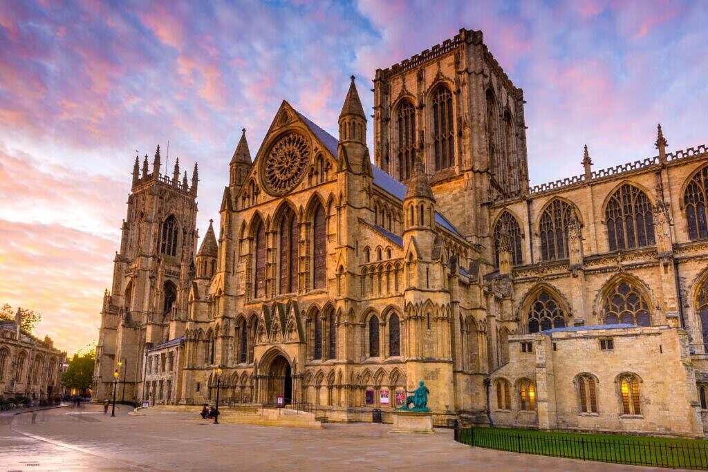 Den vackra gotiska York Minster katedralen i York, England reser sig mot en blå, rosa och lila färgad himmel.